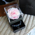 Pink preserved rose in a clear display box with a drawer holding a blue beaded bracelet.
