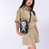 Woman wearing beige short-sleeve shirt and pleated skirt with a black skeleton crossbody bag
