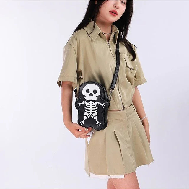 Woman wearing beige short-sleeve shirt and pleated skirt with a black skeleton crossbody bag