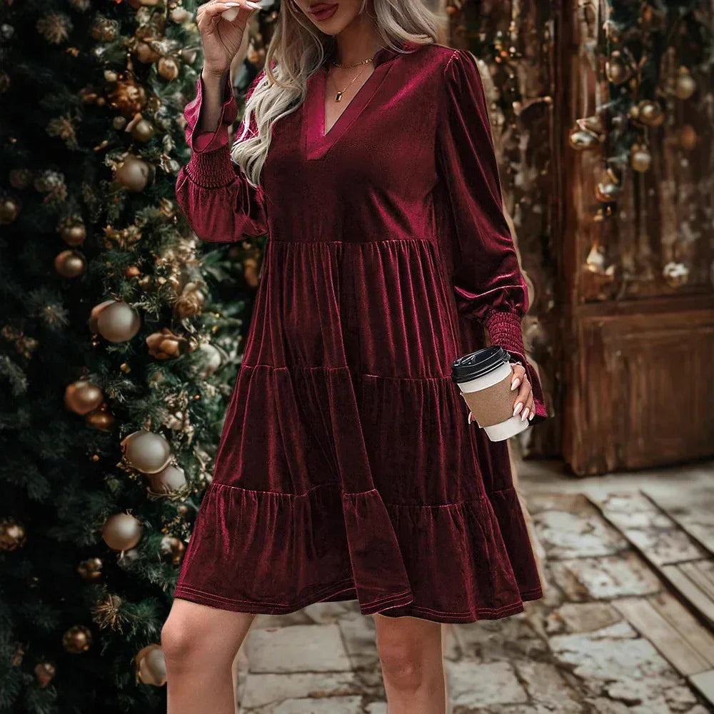 Woman in loose burgundy velvet long sleeve dress with V-neck and tiered skirt, holiday setting