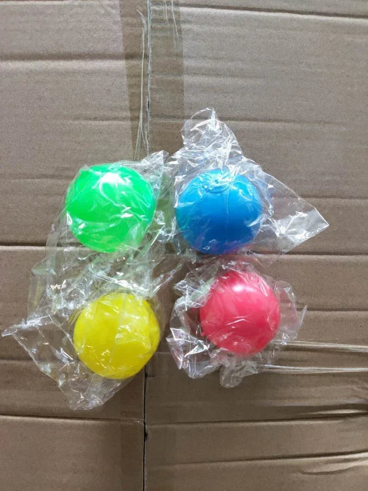 Four colorful plastic balls in green, blue, yellow, and pink, each wrapped in clear plastic.