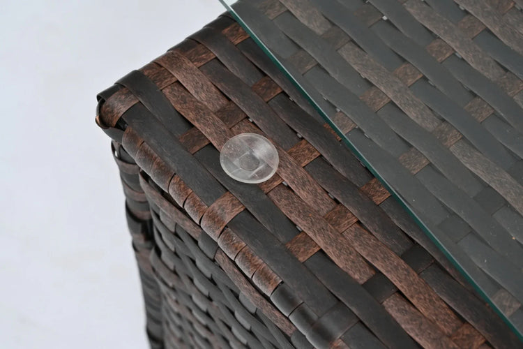 Close-up of brown woven rattan table corner with glass top and clear rubber pad