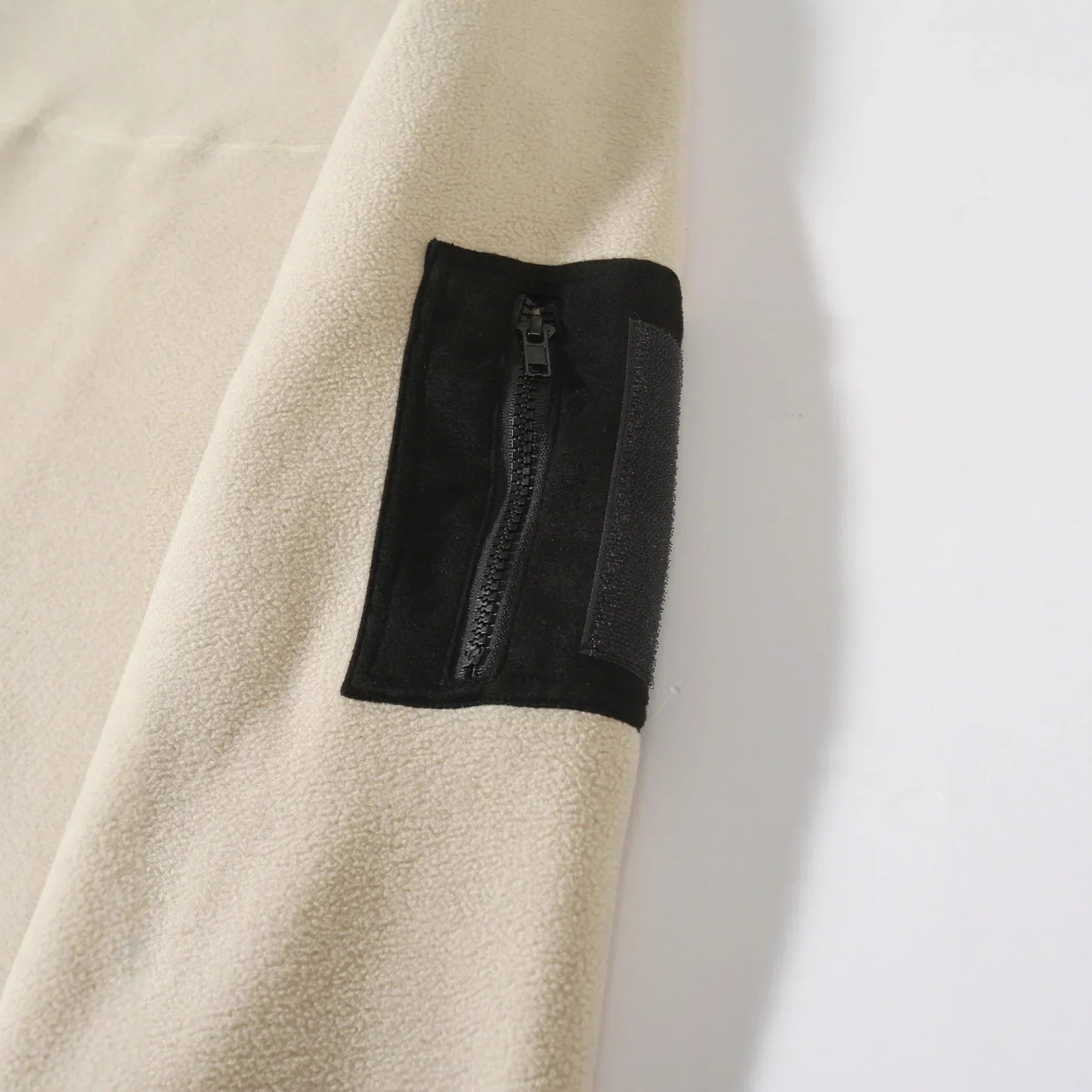 Beige fleece sleeve with black zippered pocket and relaxed fit streetwear style
