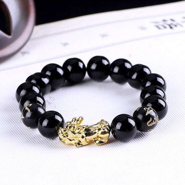 Black beaded bracelet with glossy finish and gold dragon charm, modern streetwear accessory