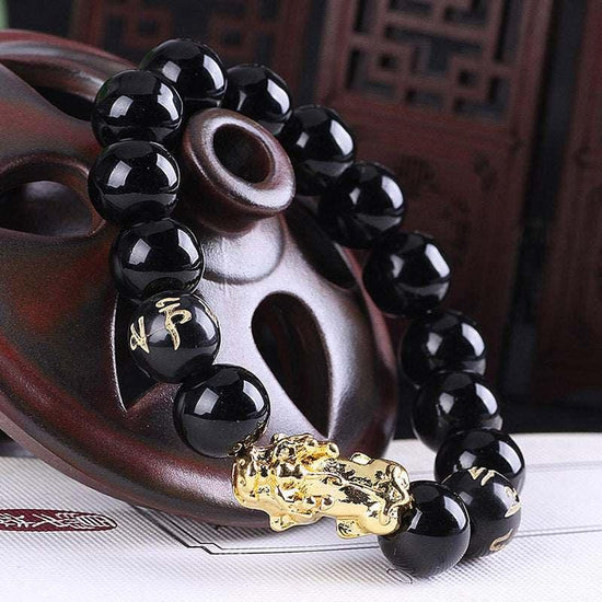 Black beaded bracelet with gold accents and engraved characters, glossy finish, loose fit