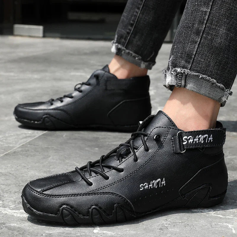 Black leather high-top sneakers with lace-up front, rugged sole, and relaxed fit, worn with rolled jeans.