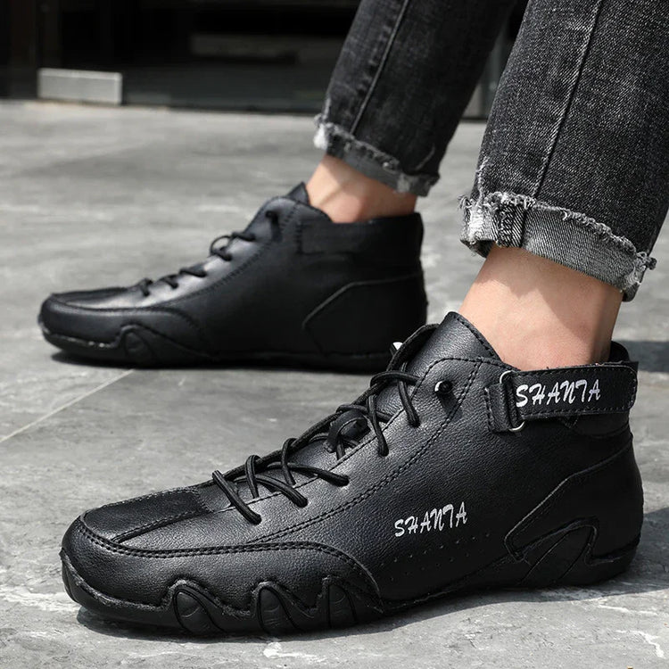 Black leather high-top sneakers with lace-up front, rugged sole, and relaxed fit, worn with rolled jeans.