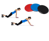 Woman in fitted black leggings and blue tank top using exercise sliders on white background