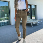 Woman wearing fitted khaki jogger pants and a white ribbed tank top outdoors