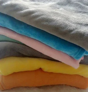 Stack of folded fleece sweaters in pastel colors, showcasing soft texture and casual fit