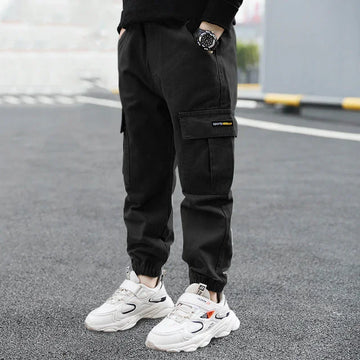 Black cargo jogger pants with relaxed fit and pockets, styled with chunky white sneakers