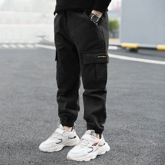 Black cargo jogger pants with relaxed fit and pockets, styled with chunky white sneakers