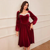 Woman wearing a red velvet midi dress with long sleeves and white faux fur trim, fit and flare style