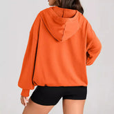 Woman wearing oversized orange hoodie with relaxed fit and black shorts, casual streetwear style.
