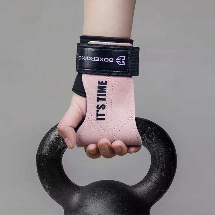 Hand wearing pink suede weightlifting wrist wrap with black strap, gripping a kettlebell