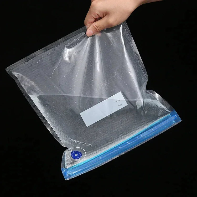 Hand holding a clear, reusable plastic vacuum storage bag with blue zipper seal