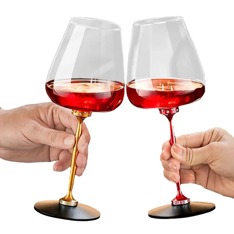 Modern wine glasses with gold and red metallic stems, filled with red wine, held in hands