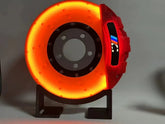 Futuristic orange and red LED disc brake lamp with metallic finish on black stand