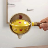 Yellow ceramic tea pot with wooden handle, dragon motif, glossy finish, traditional style.