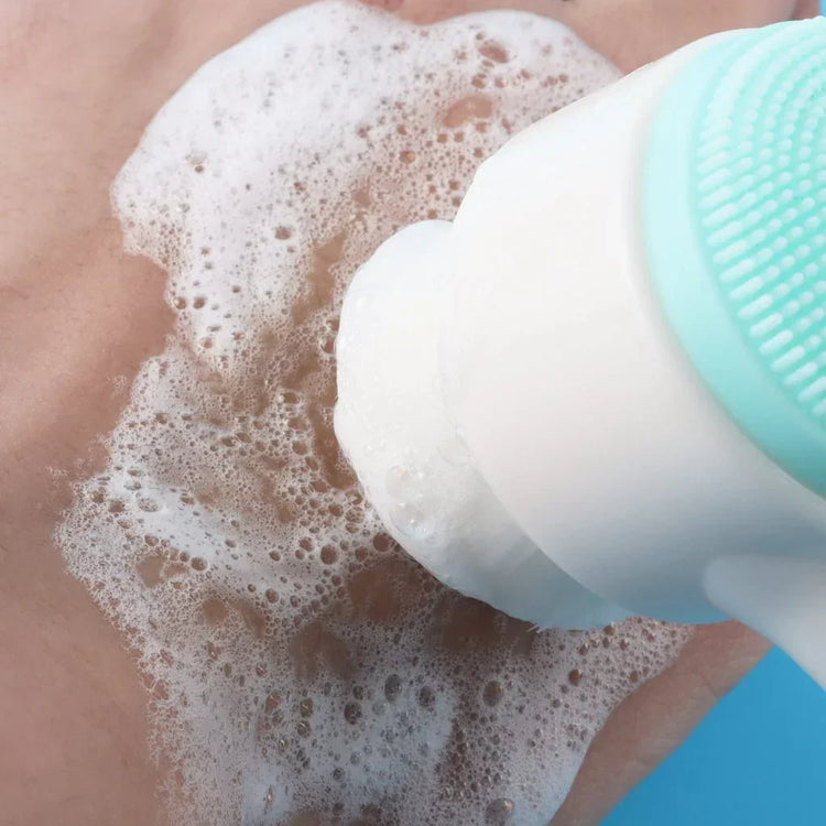 Close-up of a silicone facial brush with soft bristles creating foam on skin