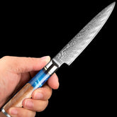 Hand holding a Damascus steel knife with blue resin and wood handle, sleek and ergonomic fit