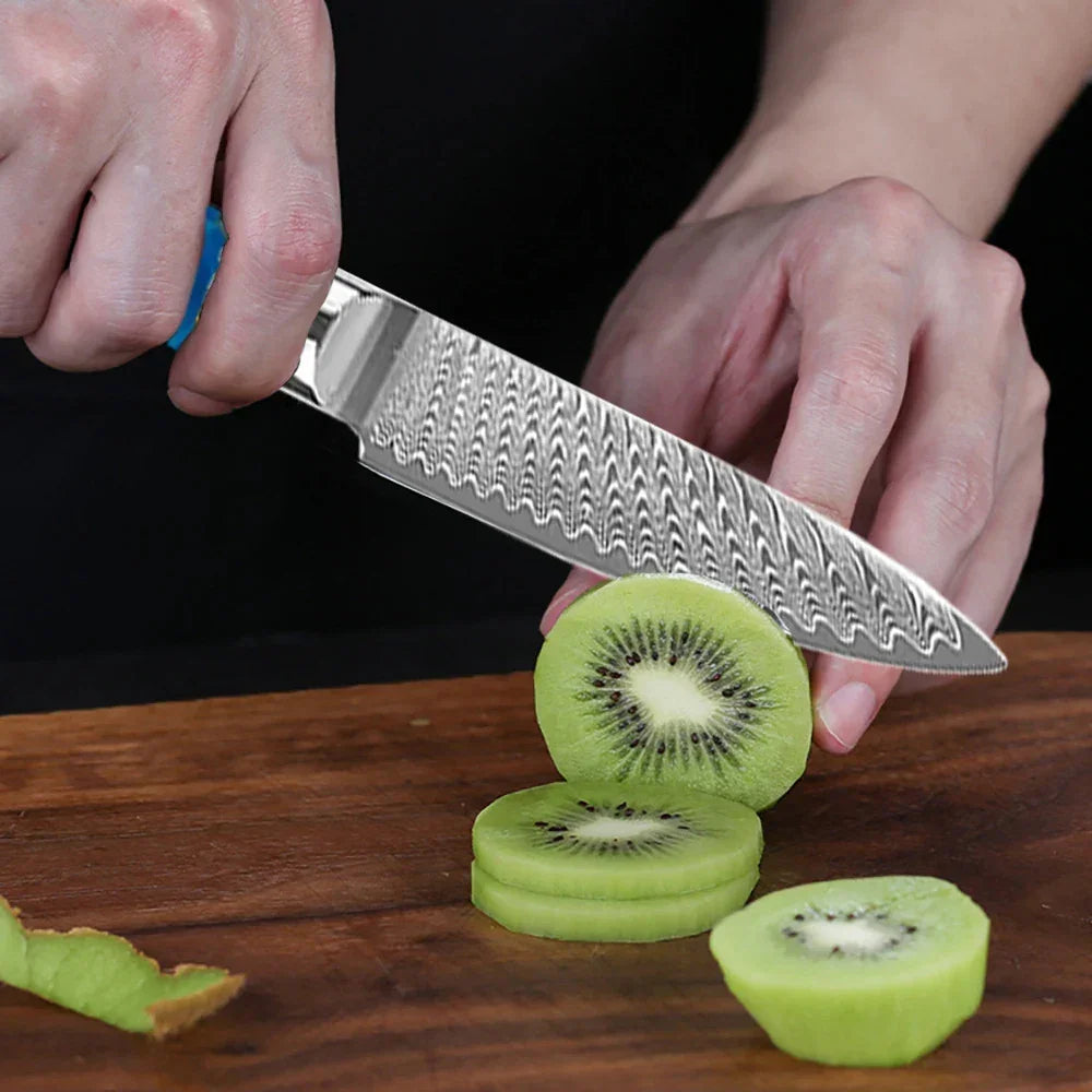 Person slicing fresh kiwi with a patterned stainless steel kitchen knife on a wooden board