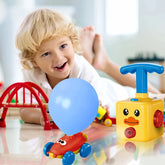 Child in white shirt playing with colorful plastic balloon car toy, lying on glossy floor