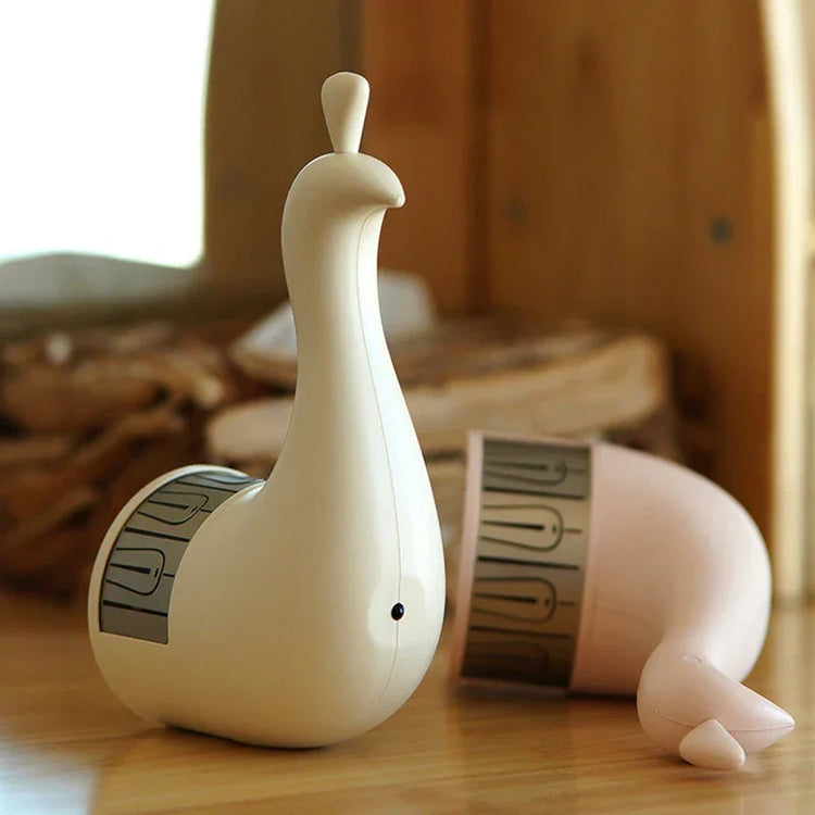 Minimalist cream and blush pink peacock-shaped plastic desk accessory on wooden surface
