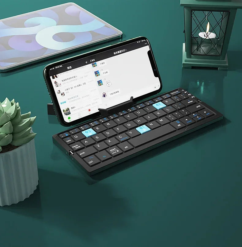 Slim black wireless keyboard with blue keys, paired with smartphone on teal desk