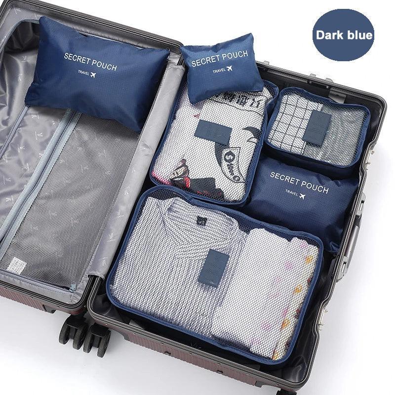 Dark blue travel packing cubes with mesh tops organizing folded clothes in a suitcase.