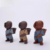 Three ceramic figurines in textured blue and beige outfits, with baskets on their backs.
