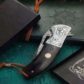 Folding pocket knife with dark wood handle, engraved silver metal, and intricate dragon design