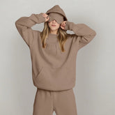 Woman in oversized beige hoodie and sweatpants set with relaxed fit, minimalist streetwear style