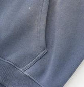 Close-up of gray cotton sweatshirt pocket with ribbed hem and relaxed fit