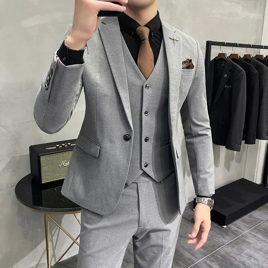 Man wearing slim fit light grey suit with matching vest, black shirt, and brown tie