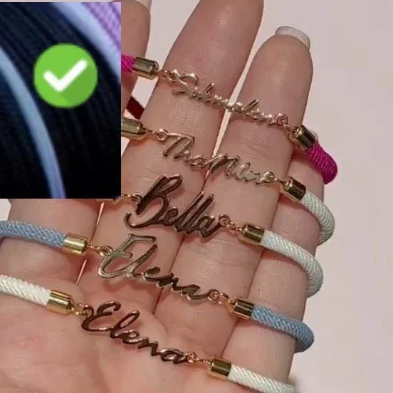 Hand holding nameplate bracelets with gold script, colorful cords, adjustable fit, trendy style