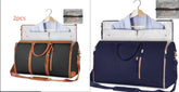 Two large duffel bags in black and navy, with leather accents, displayed open showing suit storage and hanging shirts, ideal for travel organization.