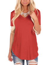 Woman wearing a loose-fit red V-neck short sleeve t-shirt and distressed blue jeans