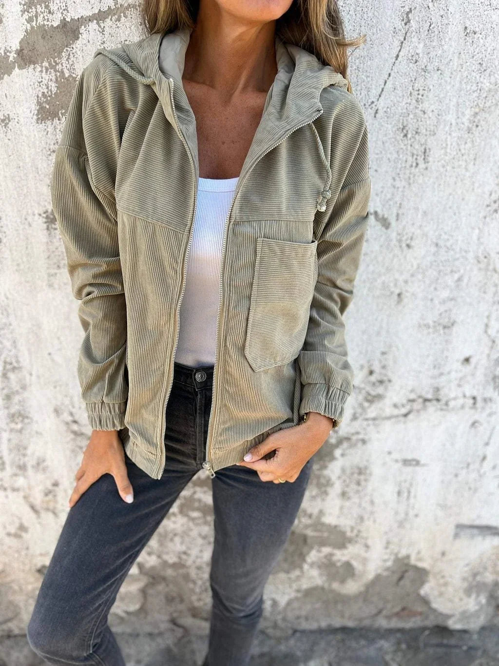 Woman wearing a beige corduroy zip-up jacket with a relaxed fit, white tank top, and black skinny jeans