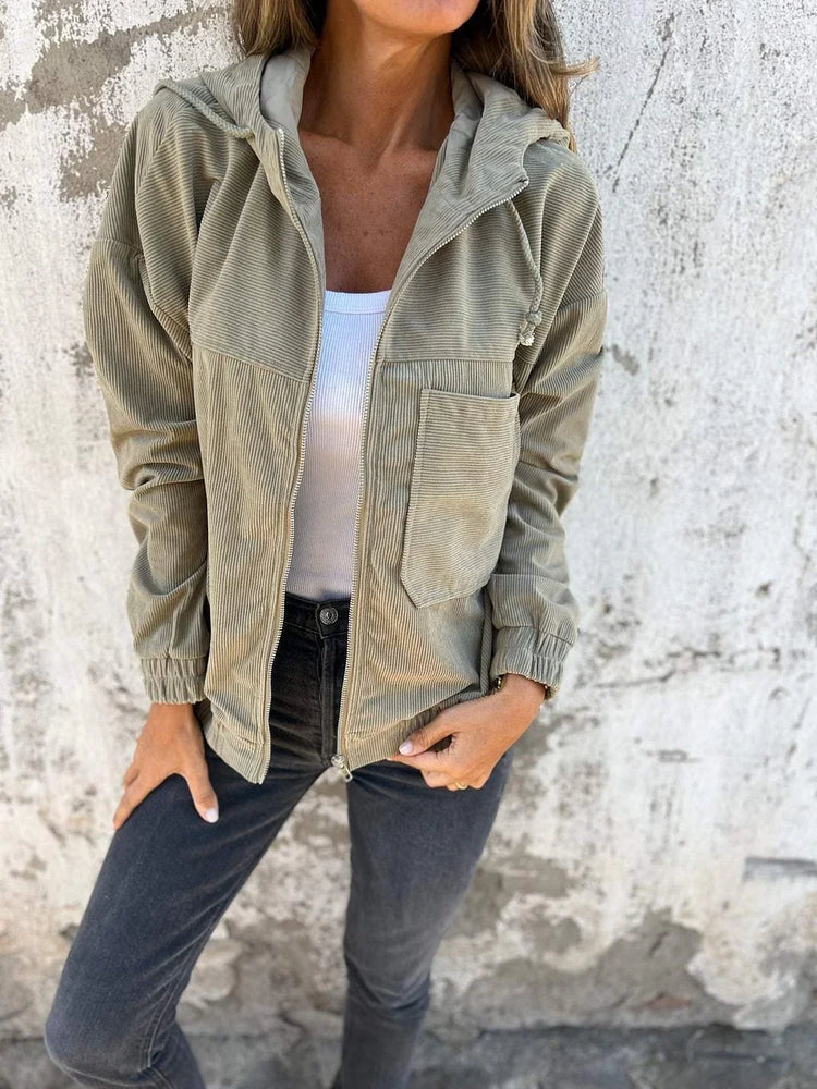 Woman wearing a beige corduroy zip-up jacket with a relaxed fit, white tank top, and black skinny jeans