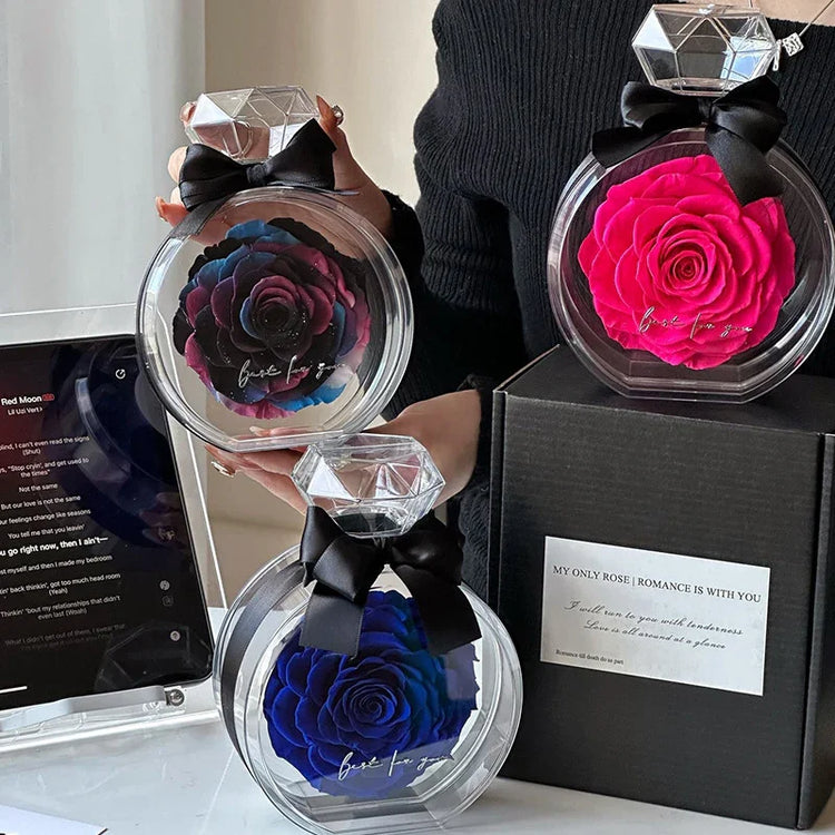 Woman in fitted black ribbed sweater holding colorful artificial roses in clear round cases with diamond-shaped tops and black bows.