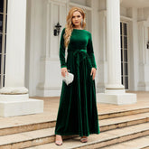 Woman in emerald green velvet long-sleeve maxi dress with tie waist, elegant fit