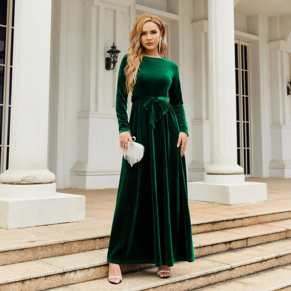 Woman in emerald green velvet long-sleeve maxi dress with tie waist, elegant fit