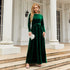 Woman in emerald green velvet long-sleeve maxi dress with tie waist, elegant fit