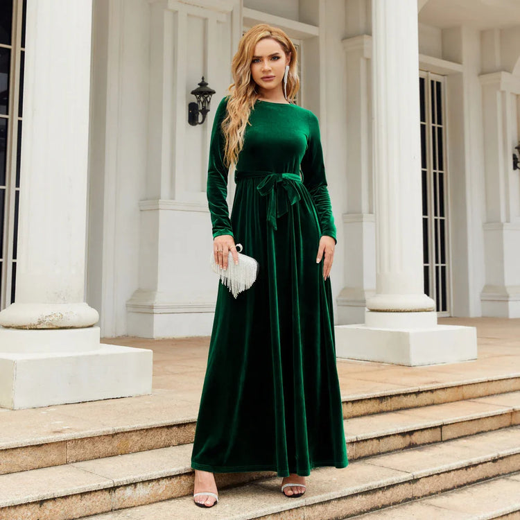 Woman in emerald green velvet long-sleeve maxi dress with tie waist, elegant fit