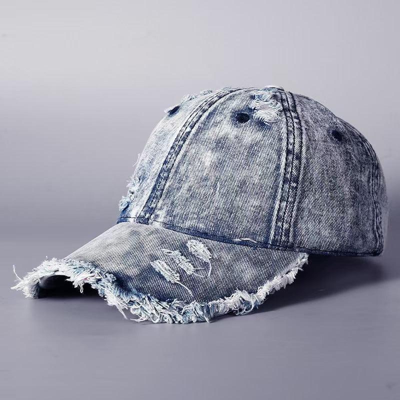 Distressed blue denim baseball cap with frayed edges and ripped details, casual streetwear style