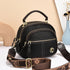 Black faux leather crossbody bag with gold zippers, adjustable printed strap, and top handle