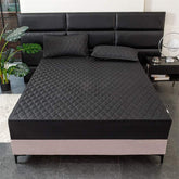 Black quilted fitted bed cover set with matching pillowcases on modern bed