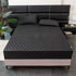 Black quilted fitted bed cover set with matching pillowcases on modern bed
