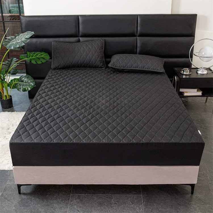 Black quilted fitted bed cover set with matching pillowcases on modern bed